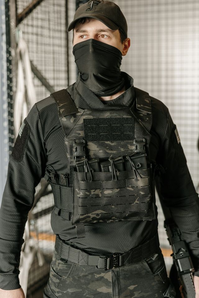 Joueur d'airsoft équipé d'un masque et d'un gilet tactique, tenue typique d'un pack de location