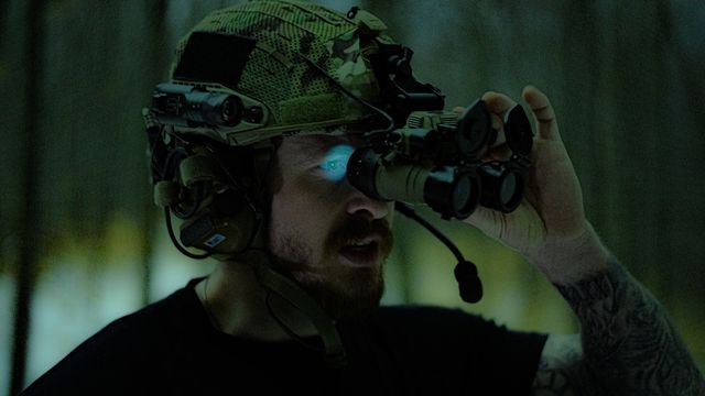 Joueur airsoft équipé d'une vision nocturne et d'un casque tactique pendant une opération de nuit en forêt