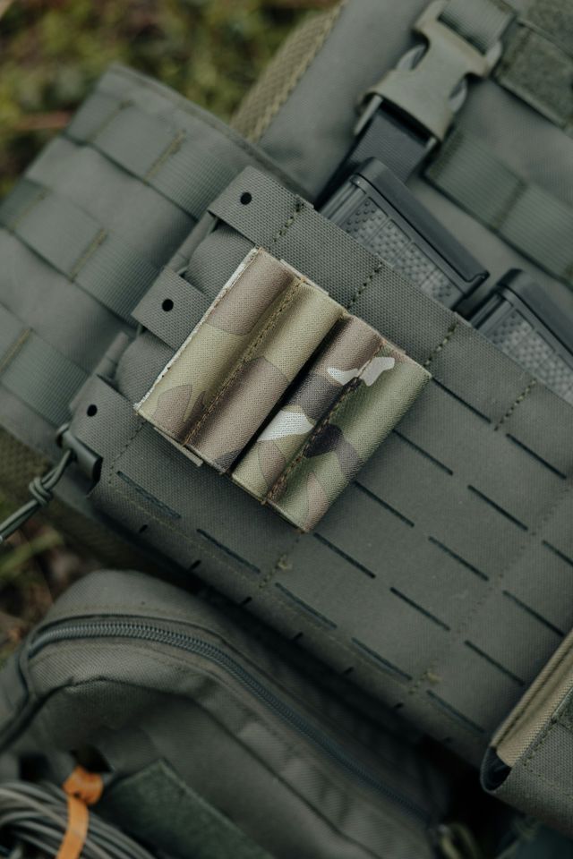 Gilet tactique ranger green et chargeur posés à plat, matériel airsoft prêt à être rangé pour le transport