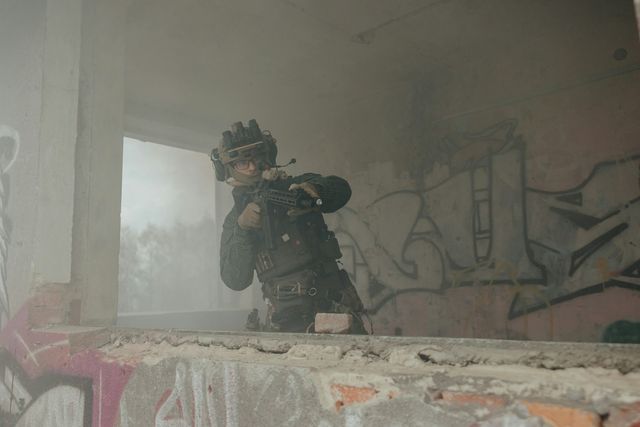 Joueur d'airsoft en position de tir dans un bâtiment couvert de graffitis