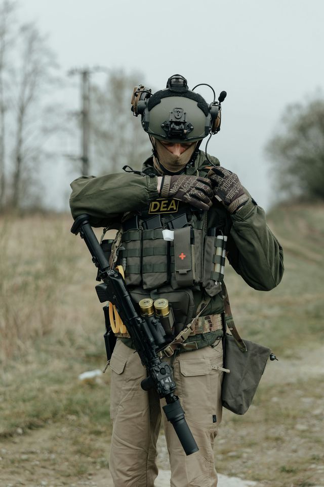 Joueur d'airsoft ajustant son équipement, réplique en main