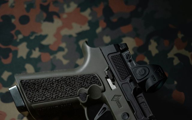 Pistolet airsoft à gaz posé sur un tissu à motif camouflage