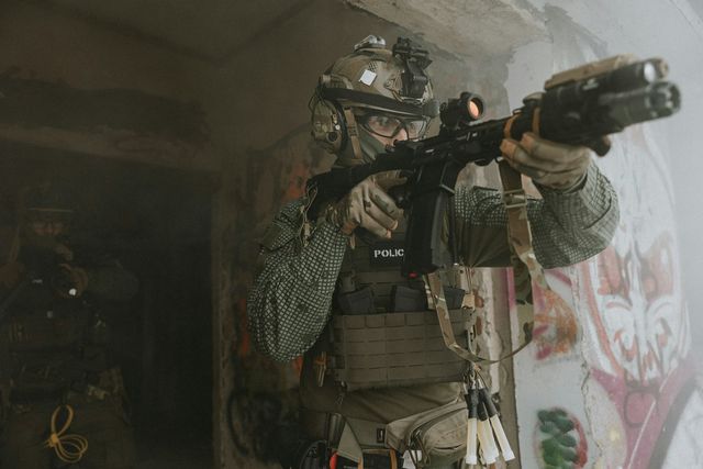 Canon d'une réplique airsoft tenue en joue dans l'encadrement d'une porte