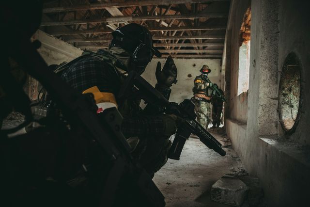 Joueurs d'airsoft équipés progressant dans un bâtiment en ruine, en clair-obscur