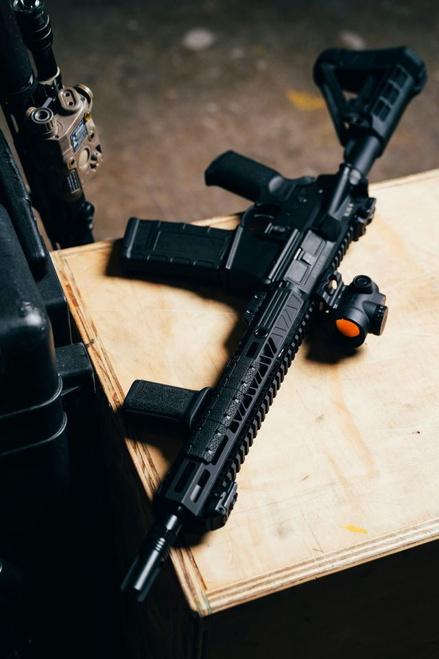 Réplique airsoft noire posée sur une table en bois, configuration typique d'une revente d'occasion entre joueurs