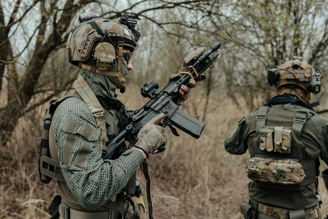 Deux joueurs en tenue camouflage avec leurs répliques airsoft en extérieur