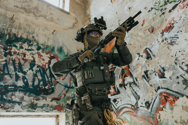 Joueur d'airsoft en tenue tactique, réplique en main, progressant dans un bâtiment