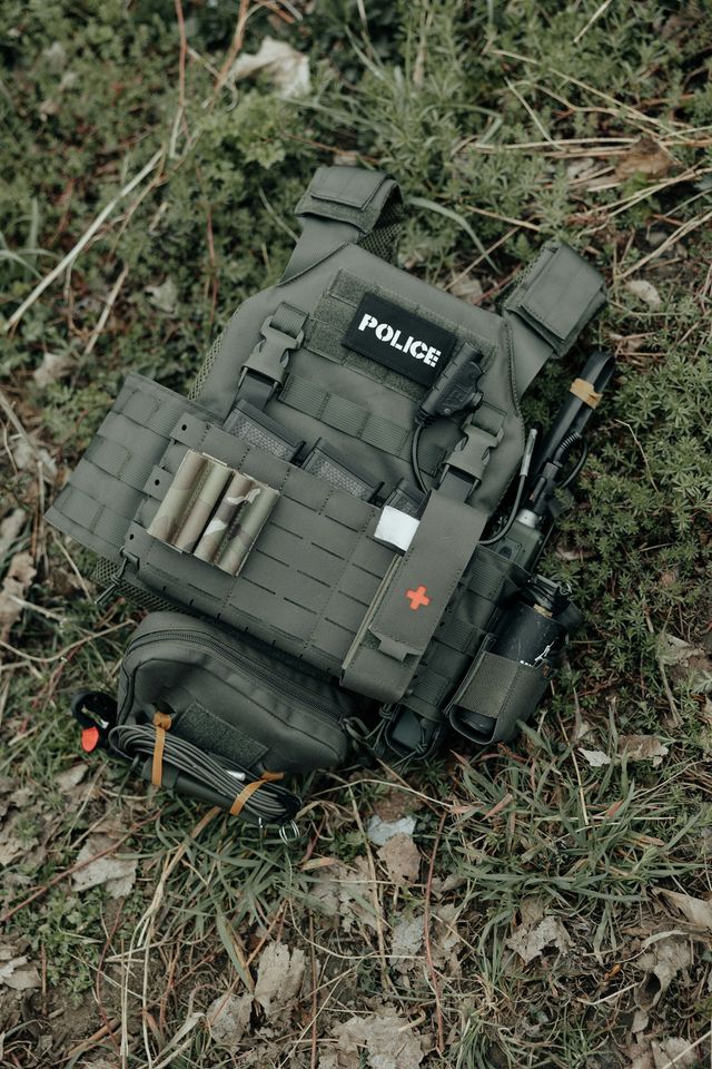 Gilet tactique d'airsoft avec kit médical et radio, équipement posé à plat