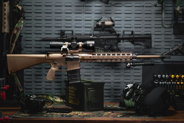 Réplique airsoft posée sur une table de préparation avec chargeur, casque et matériel de contrôle