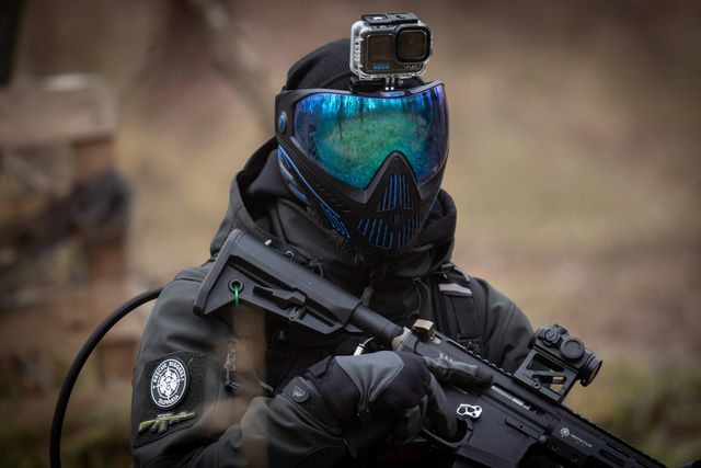 Joueur airsoft portant un masque intégral à écran thermique teinté, réplique M4 en main