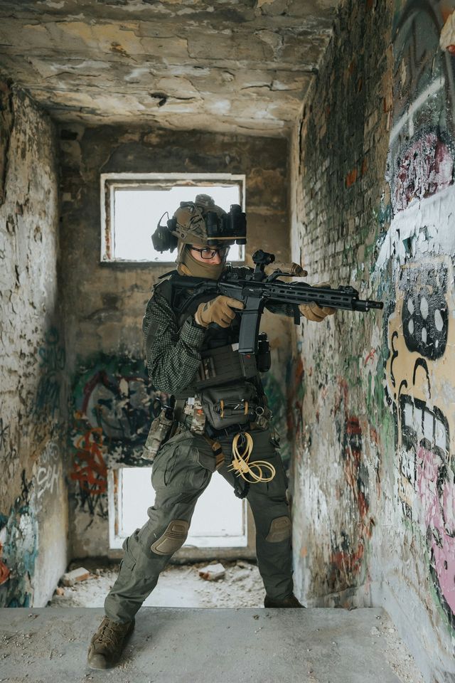 Joueur d'airsoft en tenue tactique visant dans un bâtiment désaffecté
