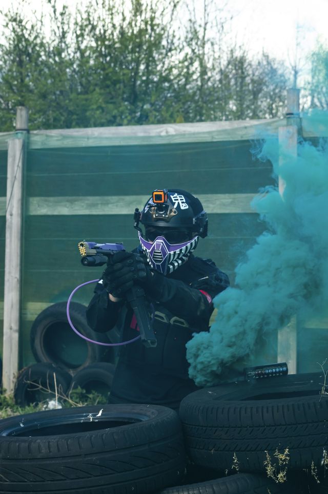 Joueur tenant un lanceur de paintball avec masque intégral, en position de tir