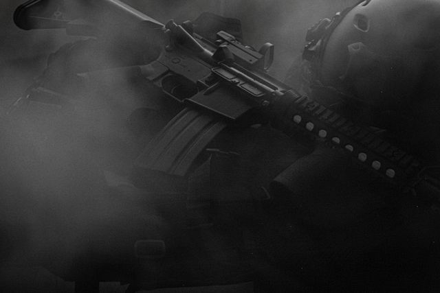 Réplique airsoft type fusil d'assaut noire posée sur un tissu sombre, vue de dessus
