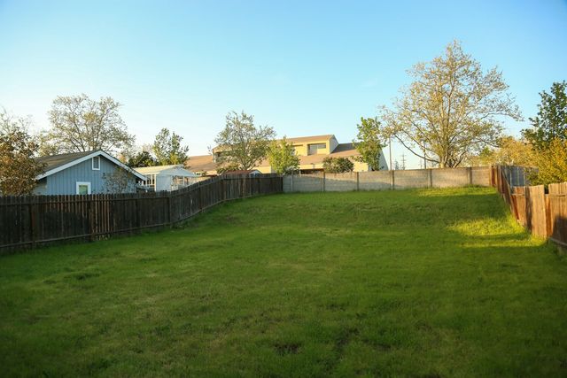 Jardin engazonné bordé d'une palissade en bois, avec des maisons à l'arrière-plan